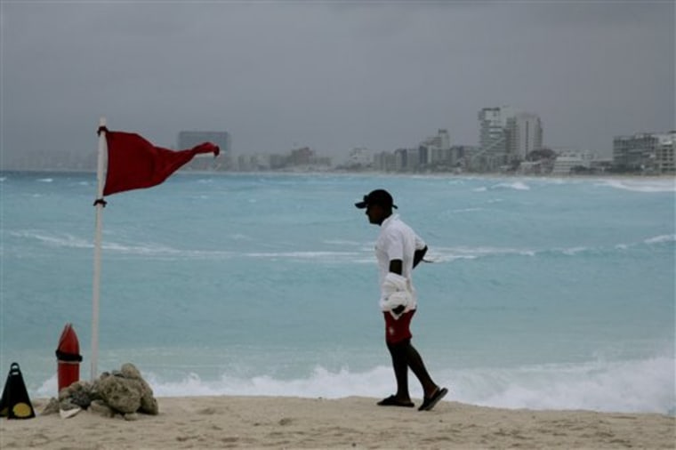 A life-guard stands next to a red flag meaning high hazard of high surf and/or strong currents as tropical storm Alex nears the region in the resort city of Cancun, Mexico, Saturday, June 26, 2010. The weather was deteriorating in Belize, Mexico, and along the Yucatan Peninsula, the national hurricane center said, noting that it is too soon to say if Alex would hit the massive oil spill in the Gulf of Mexico.  (AP Photo/Israel Leal)